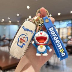 Hand holding a gac aion y plus key cover featuring a doraemon design, including a blue strap and a cute doraemon charm.