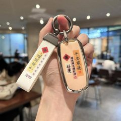 A hand holds a geely panda mini car key cover featuring chinese characters for good fortune and safety, paired with a matchin...