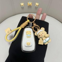 A hand holds a changan cs75 plus car key cover featuring a cute bear design with a matching keychain, set against a clean, mi...