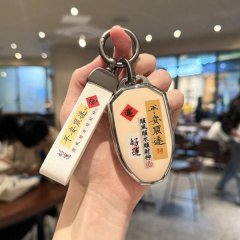 A hand holds a gac gs3 car key cover featuring chinese characters for good fortune and safety, paired with a matching keychai...