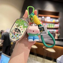 Hand holding a gac trumpchi gs4 key cover featuring a cartoon design and a matching keychain, displayed in a cozy cafe settin...
