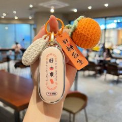 A hand holds a li auto l9 car key cover with a premium silicone shell, featuring a good luck design and a crocheted orange ch...