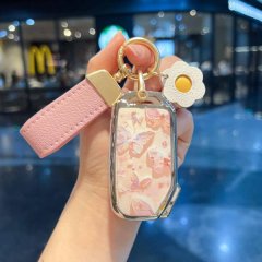A hand holds a stylish kia key cover featuring a pink floral design with butterflies, complemented by a matching pink strap a...
