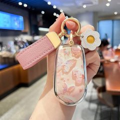 A hand holds a stylish ora good cat car key cover featuring a pink butterfly design, complemented by a matching pink strap an...