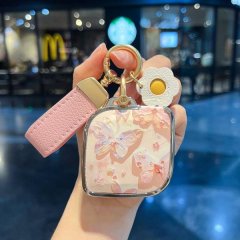 A hand holds a lynk & co 08 car key cover featuring a pink leather strap and a square shell with a butterfly design, perfect ...