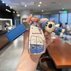A hand holds a buick enclave car key cover featuring a soft-touch shell with a dachshund design and a matching plush keychain...