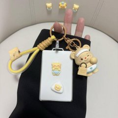 A hand holds a white card key cover featuring cute bear designs, including a bear with a cream bear tag and another bear in a...