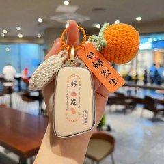 A hand holds a stylish chery ant eq1 car key cover with a good hair design, accompanied by a crocheted orange and tag, set in...