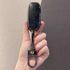 A hand holds a sleek, transparent denza d9 2025 car key cover with a minimalist design, featuring a black key fob and a metal...