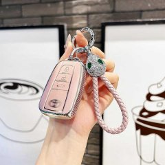 A hand holds a stylish toyota key cover in pink leather, featuring a decorative snake head charm and braided rope, designed f...