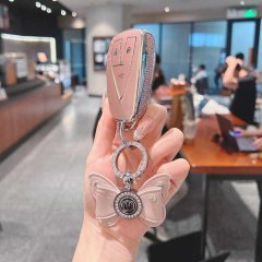 A hand holds a stylish pink key cover for the changan cs75 plus, featuring a butterfly charm and elegant design, perfect for ...