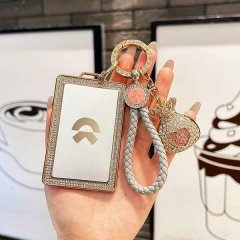A hand holds a stylish nio es6 nfc card key cover with a diamond-encrusted frame and a braided rope keychain, featuring a sle...