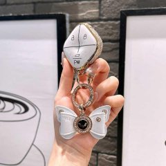 A hand holds a stylish wuling binguo key cover mini, featuring a white and gold design with a butterfly charm, perfect for en...