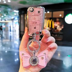 A hand holds a pink, glittery skoda key cover with a volkswagen logo butterfly charm, designed for models like rapid, octavia...