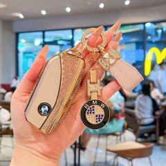A hand holds a luxurious bmw key cover with a sparkling design, featuring a bmw logo and a matching keychain, perfect for x1-...