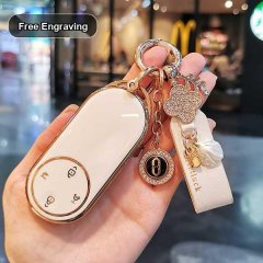 Hand holding a white huawei aito m9 key cover with free engraving, featuring a leather strap and decorative charms.