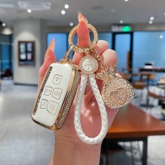Elegant land rover defender key cover for women, featuring a white and gold design with rhinestone accents and a stylish brai...
