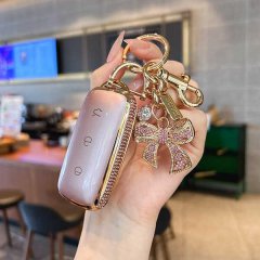 A hand holds a pink galaxy l7 key cover with gold accents and a sparkling bow charm, designed for geely models like the l6/e8...