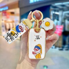 A hand holds a stylish mg rx5 plus key cover featuring a cartoon character in a yellow outfit, paired with a decorative flowe...