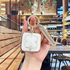 A hand holds a zeekr 001 bluetooth smart key cover, featuring a sleek white and gold design with a diamond-encrusted keychain...