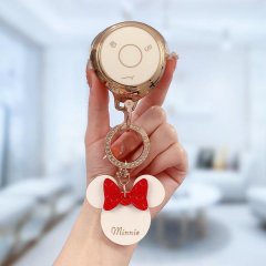 A hand holds a nio v key cover featuring a minnie mouse design with a red bow and minnie text, attached to a gold keychain wi...