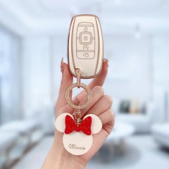A hand holds a lincoln key cover for aviator, nautilus, navigator, featuring a minnie mouse charm with a red bow and minnie t...