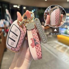 Elegant roewe rx5 key cover featuring a pink monogram design, gold accents, and a decorative strap with a bear charm, shown f...