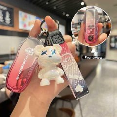 A hand holds a stylish porsche key cover with a gradient pink design and a cute bear charm, showcasing both the front view an...