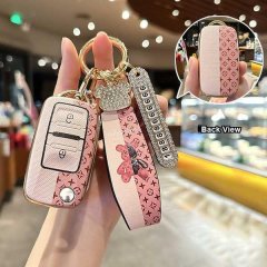 A hand holds a stylish tiejiangjun kd vvdi foldable key cover with a pink and gold design, featuring a decorative strap and a...