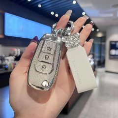 A hand holds a ford key cover for focus, ecosport, and mondeo, featuring a sleek silver design with a glittery texture and a ...
