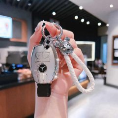 A hand holds a mercedes-benz key cover for models like the c200l, glc300, and a-class, featuring a sleek silver design with a...