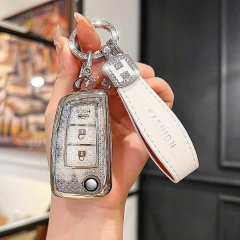 A hand holds a sleek, silver nissan sylphy classic 1.6 key cover with a 3-button foldable design, paired with a white leather...