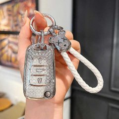 A hand holds a stylish hyundai key cover with a glittery finish, featuring a white braided lanyard and a decorative charm, de...