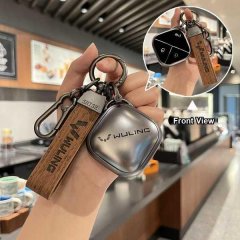 A hand holds a wuling binguo key cover, showcasing its sleek design with a wooden tag and soft tpu case, highlighted in a fro...
