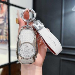 A hand holds a stylish zerorun t03 key cover for 2023 c1/s01 co1 remote, featuring a glittery silver design and a white leath...