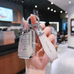 A hand holds a stylish volkswagen cc key cover with a fashion leather strap, featuring a sleek silver design and diamond acce...