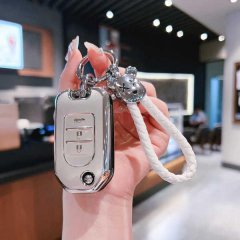 A hand holds a sleek, metallic honda key cover for 9.5th gen accord, civic, cr-v & hr-v, featuring a stylish white braided la...