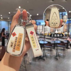 A hand holds a stylish changan cs55 key cover with elegant chinese characters and a decorative strap, showcased in a cozy caf...