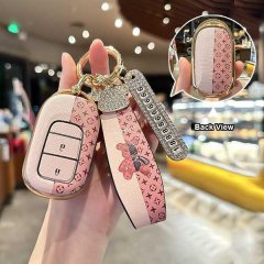 Elegant honda key cover for cr-v, accord, hr-v featuring a pink leather design with gold accents and a decorative strap, show...