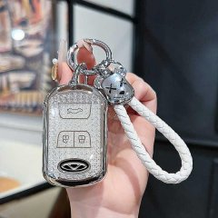 A hand holds a chery tiggo 8 key cover, featuring a sleek silver design with a textured finish and a white braided lanyard. t...