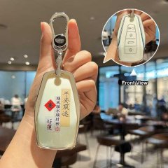 A hand holds a geely key set in a stylish silicone case, featuring chinese characters for good luck and safety. the front vie...