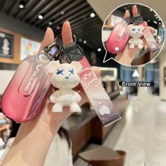 Hand holding a wuling hongguang mini ev key cover with a gradient pink design and a cute bear charm, shown in front view.