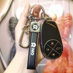 A hand holds a sleek nio es6 key cover, featuring a black leather strap with the nio logo and a metallic carabiner, designed ...