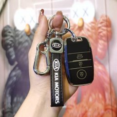 A hand holds a sleek black kia key cover with kia motors branding, featuring a carabiner and buttons for locking, unlocking, ...