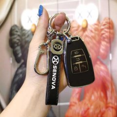 A hand holds a sleek black key cover for the baic senova d50, d70, x55, and x65 models, featuring a senova strap and a modern...