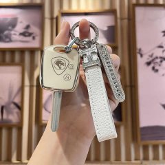 A hand holds a proton remote key cover for l3 & l5, featuring a premium lotus-embossed design with a sleek white leather stra...