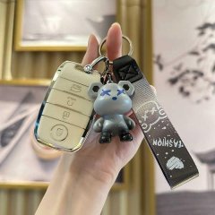 A hand holds a kia sorento key cover with a 4-button smart key, featuring a stylish bear charm and a fashion strap, set again...