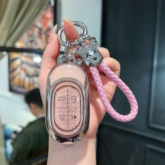 A hand holds a jetour shanhai l9 key cover, featuring a sleek pink leather shell with a braided strap and a decorative skull ...