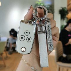 A hand holds a stylish key cover for honda odyssey and cr-v, featuring a tpu protector with a sleek white design, diamond-enc...