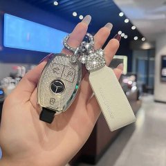 A hand holds a mercedes-benz e300l key cover, featuring a sleek silver design with sparkling embellishments and a matching le...